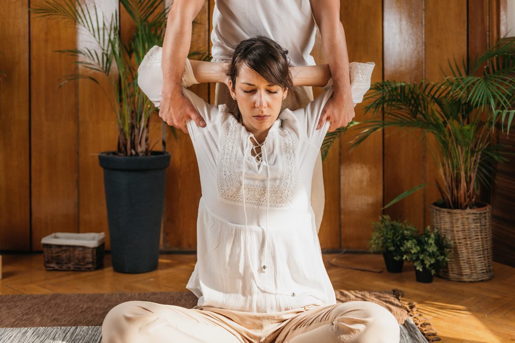 Therapist assisting a woman with an overhead stretch during Bali stretch therapy at The Bali Spa, a spa in Hyderabad