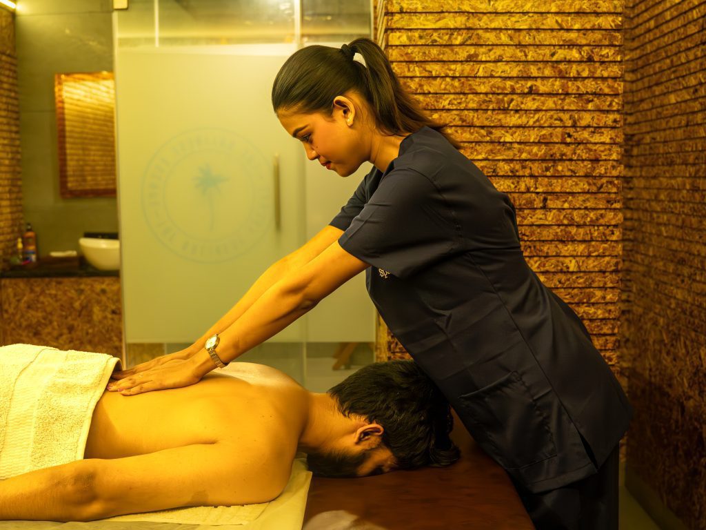 Therapist applying pressure to a man's back and shoulders during a massage at The Bali Spa, a spa in Hyderabad