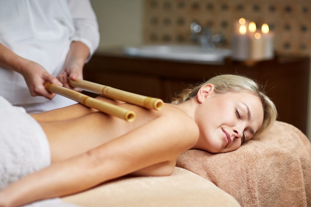 Therapist using bamboo massage sticks on a woman's back during a spa treatment at The Bali Spa, a spa in Hyderabad