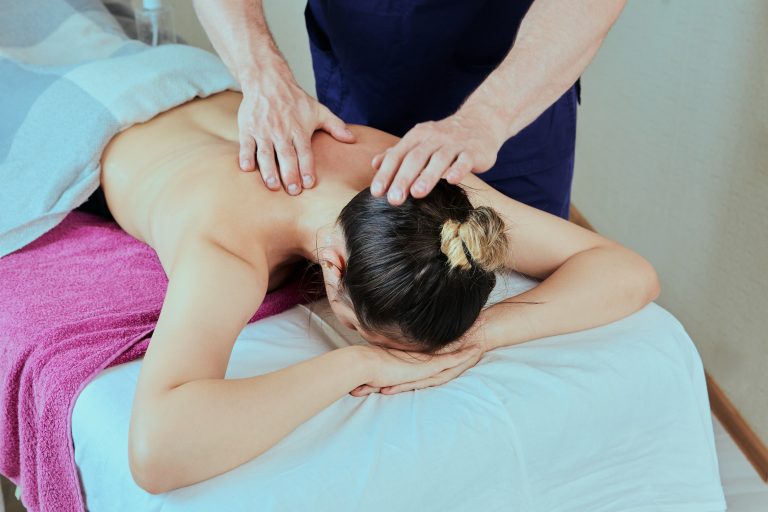 Deep tissue back, neck, shoulder massage, male masseur massages muscles of young woman