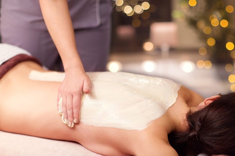 woman having back massage with cream at spa