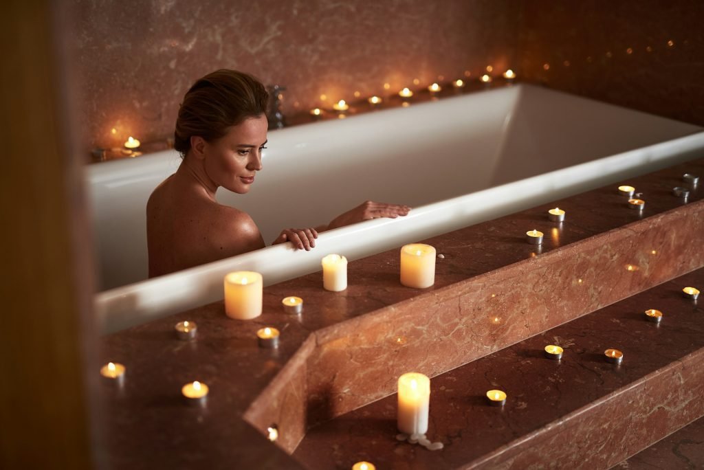 Woman relaxing in a candlelit hot tub during a spa retreat at The Bali Spa, a spa in Hyderabad