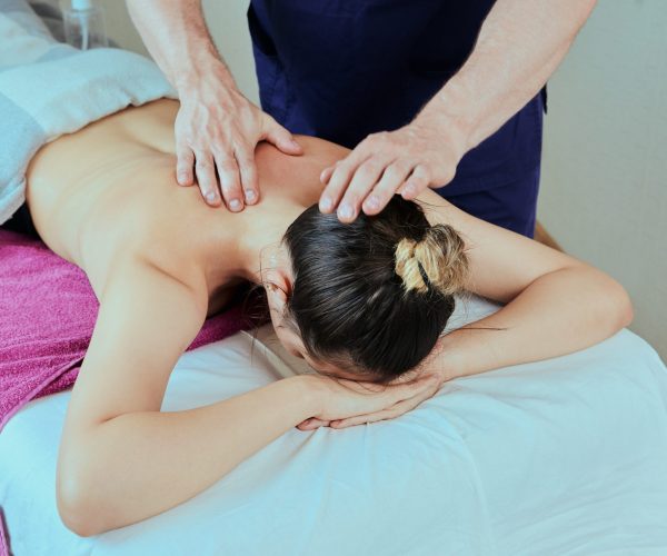 Deep tissue massage for shoulder and back pain relief of young woman.