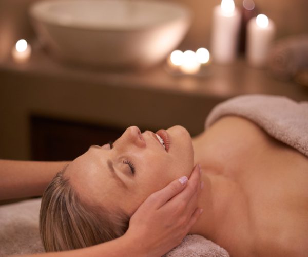 Face massage, spa and relax with woman, beauty and candles with hospitality and stress relief. Person, facial and girl with wellness or healthy with vacation or peace with holiday, detox or self care.