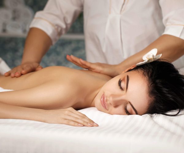 Relaxed beautiful young woman receiving massage in spa salon. Beauty treatment