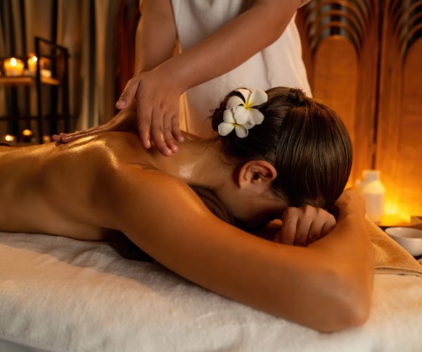 Caucasian woman customer enjoying relaxing anti-stress spa massage and pampering with beauty skin recreation leisure in warm candle lighting ambient salon spa at luxury resort or hotel. Quiescent