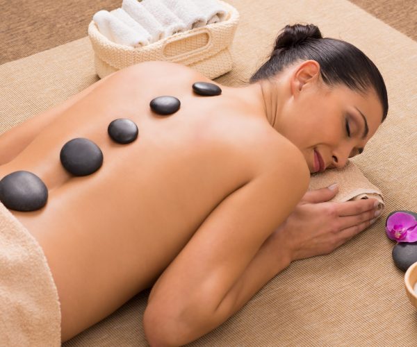Beautiful Young Woman Receiving Hot Stones Massage At Spa